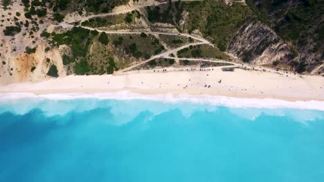 Playa-De-Myrtos-En-Cefalonia,-Grecia-Con-Aguas-Turquesas-Y-Costa-Arenosa,-Turistas-Relajándose,-Vista-Aérea