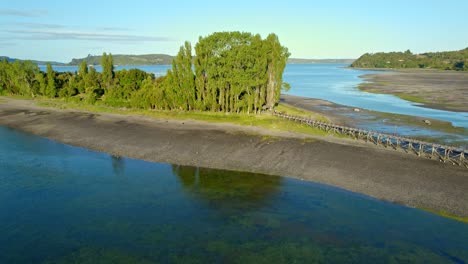 Luftaufnahme-Der-Insel-Aucar-Mit-Einem-Vogelschwarm-Im-Flug,-Grünflächen-Auf-Chiloé