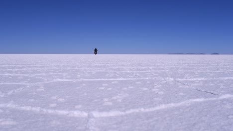 Motorradfahrer-Fährt-In-Die-Ferne-Auf-Dem-Flachen-Salzsee-Uyuni-In-Bolivien