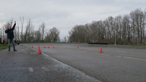 Inspector-starting-car-safety-control-exam-with-SUV-driving-through-traffic-cones-in-slippery-conditions