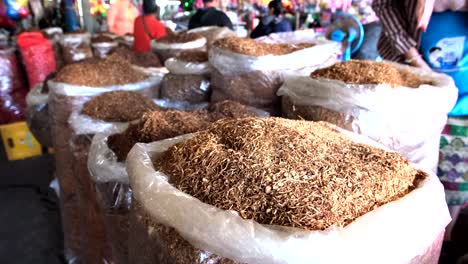 4K-shots-capture-an-array-of-shredded-tobacco-leaves-arranged-within-a-bag,-with-people-visible-in-the-background