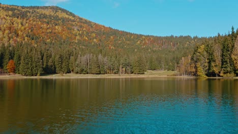 Tranquilo-Lago-Sfanta-Ana-Con-Bosque-De-Colores-Otoñales-En-Harghita,-Rumania,-Durante-El-Día