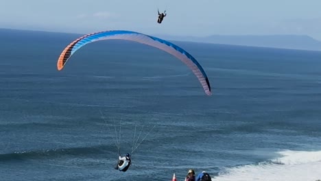 Single-para-glider-jumps-of-cliff-and-sails-away-while-a-tandem-para-glider-comes-in-for-a-very-smooth-landing-at-Torrey-Pines-Gliderport-in-La-Jolla,-California