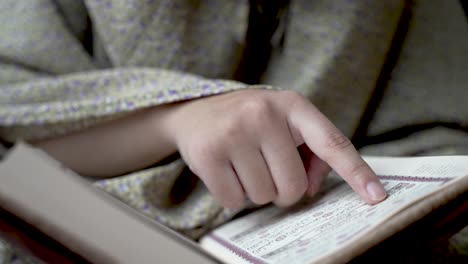 Close-Up-Of-Finger-Reading-And-Tracing-Lines-From-Quran,-symbolizing-the-pursuit-of-home-based-studying-and-learning