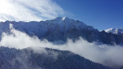 Montañas-Bucegi-Cubiertas-De-Nieve-Con-El-Pico-Bucsoiu-Y-La-Montaña-Tiganesti-Visibles-Por-Encima-De-Las-Nubes