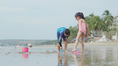 Dos-Niños-Asiáticos-Jugando-En-La-Arena-De-Una-Hermosa-Playa