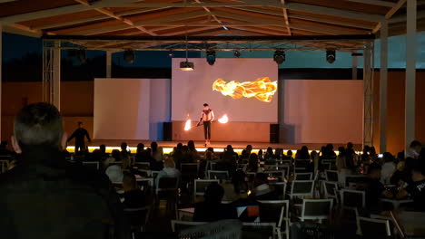 Outdoor-evening-performance-in-Sharm-El-Sheikh-with-audience-watching-a-fire-dancer-on-stage,-warm-lighting