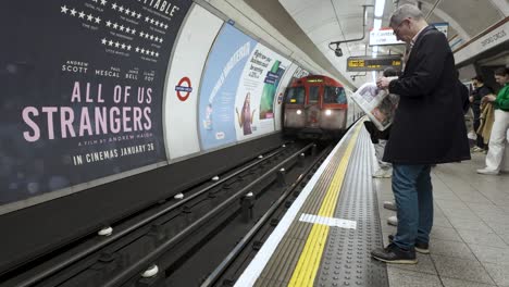 Los-Pasajeros-Observan-La-Llegada-De-Un-Tren-De-La-Línea-Bakerloo-Al-Andén-De-La-Estación-De-Oxford-Street-En-Londres,-Inglaterra,-Iluminando-El-Concepto-De-Accesibilidad-Al-Transporte-Urbano-Y-Conectividad-De-Los-Viajeros.