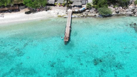 Tropical-resort-on-Playa-Kalki,-Curacao-with-clear-turquoise-waters-and-a-wooden-pier