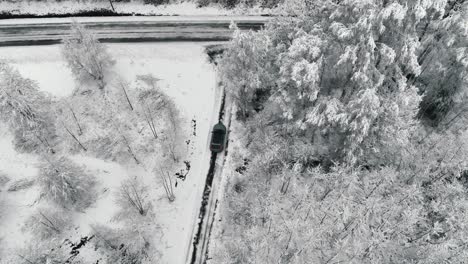 Drohnenaufnahmen-Von-Einem-Auto,-Das-Auf-Einer-Winterlichen-Waldstraße-Fährt