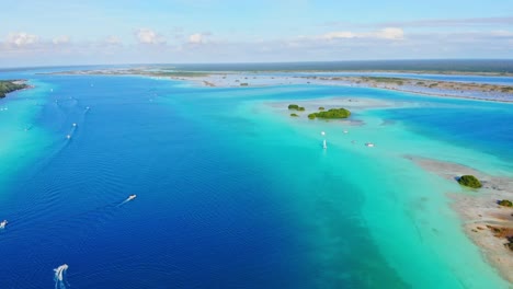 Beautiful-Tropical-Turquoise-Lagoon-at-De-Los-7-Colores-in-Mexico-with-Boats-Sailing-from-an-Aerial-Drone-Panning-Shot