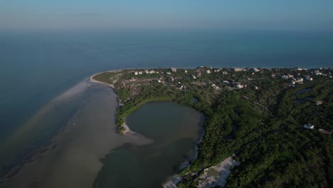 An-Aerial-drone-shot-over-Holbox,-Mexico,-revealing-lush-seaside-forests,-pristine-beaches,-and-turquoise-waters-merging-with-the-sky
