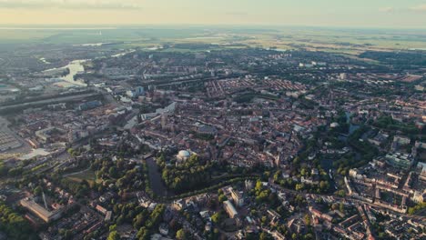 Eine-Weitläufige-Stadtlandschaft-Während-Der-Goldenen-Stunde,-Mit-Flüssen-Und-Grünflächen,-Luftaufnahme