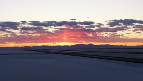 Automóviles-Circulando-Al-Atardecer-Por-La-Autopista-Cruzando-Las-Salinas-De-Bonneville-En-Utah,-EE.UU.