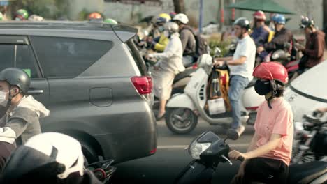 Busy-traffic-in-Ho-Chi-Minh-City-with-motorbikes-and-cars-waiting-at-a-light,-daytime