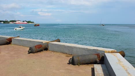 Scenic-view-from-waterfront-overlooking-historic-cannons-and-harbour-ocean-with-moored-tour-and-fishing-boats-in-capital-city-of-East-Timor,-Southeast-Asia