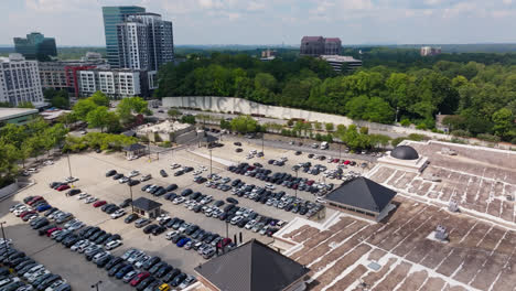 Aerial-flyover-parking-lot-with-vehicles-beside-highway-in-Buckhead-District-of-Atlanta-City,-USA