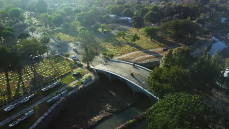 Aerial-view-around-the-bridge-over-the-creek-in-Manila-memorial-park,-in-the-sunny-Philippines