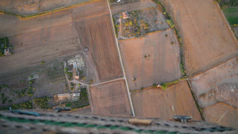 Looking-down-over-hot-air-balloon-basket-to-rural-farmland-fields-and-meadows-below