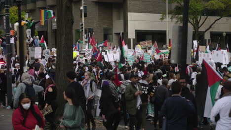 A-Wide-Shot-of-Pro-Palestine-Protestors-Marching-Through-the-Streets-Carrying-Flags,-Holding-Signs,-and-Wearing-Keffiyehs