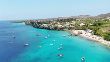 Playa-piskado-in-curacao,-turquoise-waters-with-boats-and-coastal-village,-aerial-view