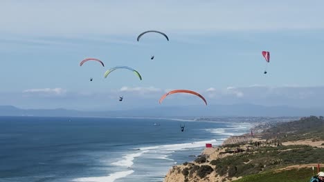 Sieben-Gleitschirmflieger-Fliegen-An-Einem-Wunderschönen-Sonnigen-Tag-Mit-Meer-Und-Klippen-Im-Hintergrund-Am-Torrey-Pines-Gliderport-In-La-Jolla,-Kalifornien