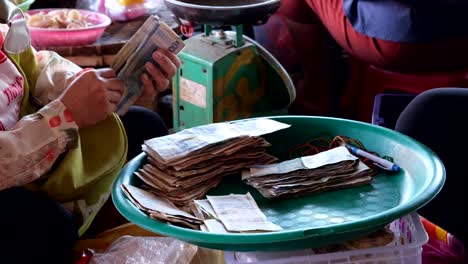 Personas-Cuyas-Identidades-Se-Desconocen-Utilizan-Sólo-Sus-Manos-Para-Contar-La-Moneda-Laosiana,-Conocida-Como-Kip-O-Lak,-Y-La-Colocan-En-Un-Recipiente-De-Plástico-En-Medio-De-Un-Ambiente-Bullicioso.