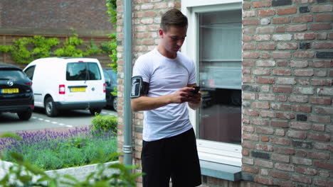Young-boy-arrives-home-after-running-stops-jog-app-on-smart-phone,-daily-routine