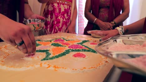 Close-up-shot-four-womens-creating-Rangoli-for-a-wedding
