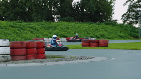 Kart-drivers-going-with-speed-over-chicane-curbstones-on-wet-circuit