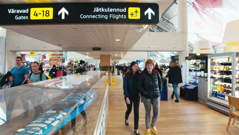 Timelapse-of-pre-COVID-busy-Tallinn-airport-terminal-with-passengers-walking-past-camera-and-guidance-signs-visible-in-ceiling