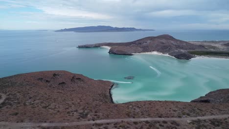 Playa-Balandra-in-Baja-California-Sur,-La-Paz,-Mexico-turquoise-waters-and-rugged-coastline-at-dusk,-aerial-view