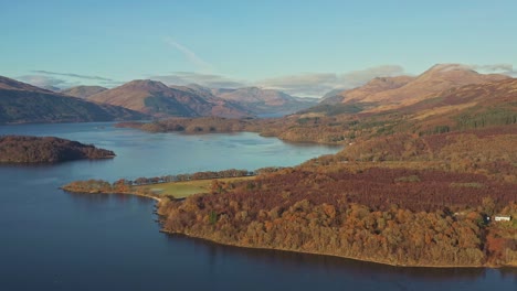 Autumn-Over-the-Lake-of-Loch-Lomond-and-The-Trossachs-National-Park-with-its-Mountainous-Hillside-of-Forests-and-Warmly-Lit-Sunlight-from-an-Aerial-Drone,-Scotland