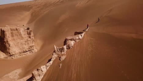 fly-over-a-big-rock-cliff-surrounded-by-desert-sand-dune-in-lut-geopark-natural-heritage-in-UNESCO-world-list-adventure-hiking-in-dry-climate-golden-hills-in-Iran-scenic-Arabian-natural-landscape