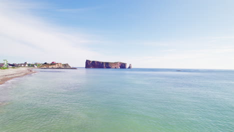 Drone-view-receding-from-Percé-Rock-above-the-Saint-Lawrence-River-during-a-sunny-day