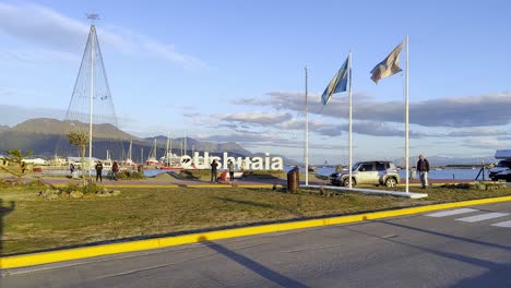 Blick-Auf-Den-Sonnenuntergang-über-Dem-Ushuaia-Buchstabenschild-Und-Dem-Weihnachtsbaum-Mit-Lichtern-Auf-Der-Plaza-Republica-Del-Peru