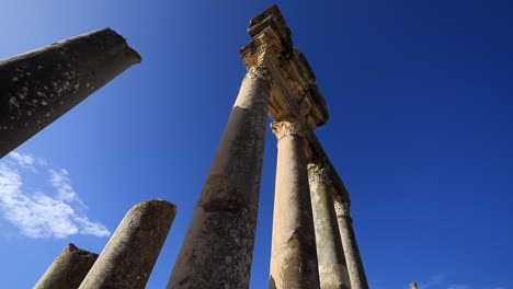 Low-angle-view-of-ancient-Roman-ruins-against-a-clear-blue-sky-in-Dougga,-Tunisia,-sunlit