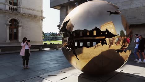 Junge-Frau-Umrahmt-Die-Kugel-In-Der-Kugel-Bronzeskulptur-Am-Dublin-Trinity-College