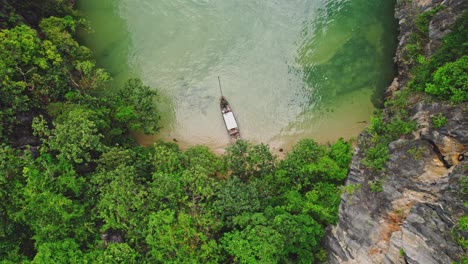 Aufsteigende-Luftdrohne-Zeigt-Ein-Longtail-Boot-Inmitten-Atemberaubenden-Türkisfarbenen-Wassers-Und-Kalksteinfelsen-Bei-Blue&#39;s-Hong,-Ko-Roi,-Thailand