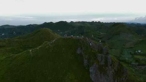 Landscape-of-contrasted-tropical-jungle-hills-above-stormy-light-blue-cloudy-skyline,-southeast-asian-environmental-drone-aerial-shot