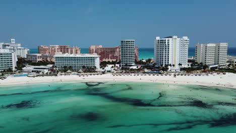 Cancun-beach-with-crystal-clear-waters-and-bustling-resort-area,-daylight,-aerial-view