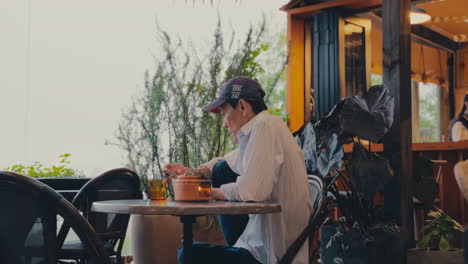 Elderly-Man-Engaged-with-Smartphone-in-Coffee-Shop-Garden