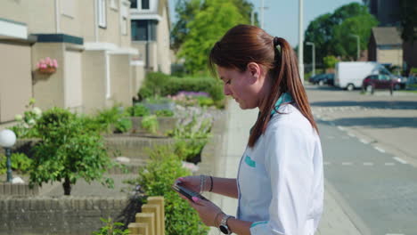 Woman-nurse-grabbing-smart-phone-in-front-of-patient-home-for-elderly-service