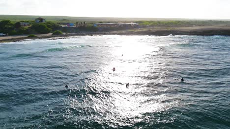 Las-Olas-Del-Océano-Rompen-Mientras-Los-Surfistas-Esperan-En-Playa-Kanoa-Curazao-Al-Atardecer.