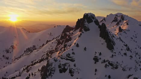 Golden-sunset-over-Tigaile-Mari-peak-in-Ciucas-Mountains,-snowy-landscape