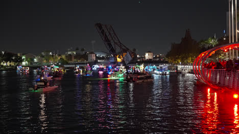 Christmas-Boat-Parade-At-Night-On-Hillsborough-River-Near-Vertical-Lift-Bridge-In-Tampa,-Florida