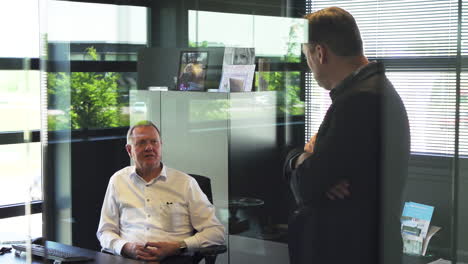 Boss-and-employee-having-a-quick-meeting-in-glass-office,-business-meeting