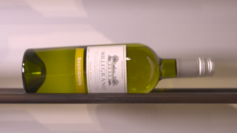 Bottle-of-Sauvignon-white-wine-lying-on-side-on-steel-shelf,-Millegrand