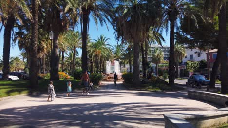 Father-and-children-walk-in-park-with-fountain-in-summertime-Antibes