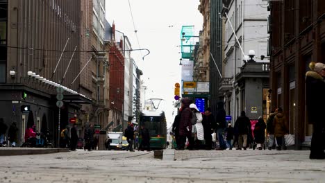 Urban-street-scene-with-tram-and-pedestrians-in-Helsinki,-overcast-day,-street-level-view